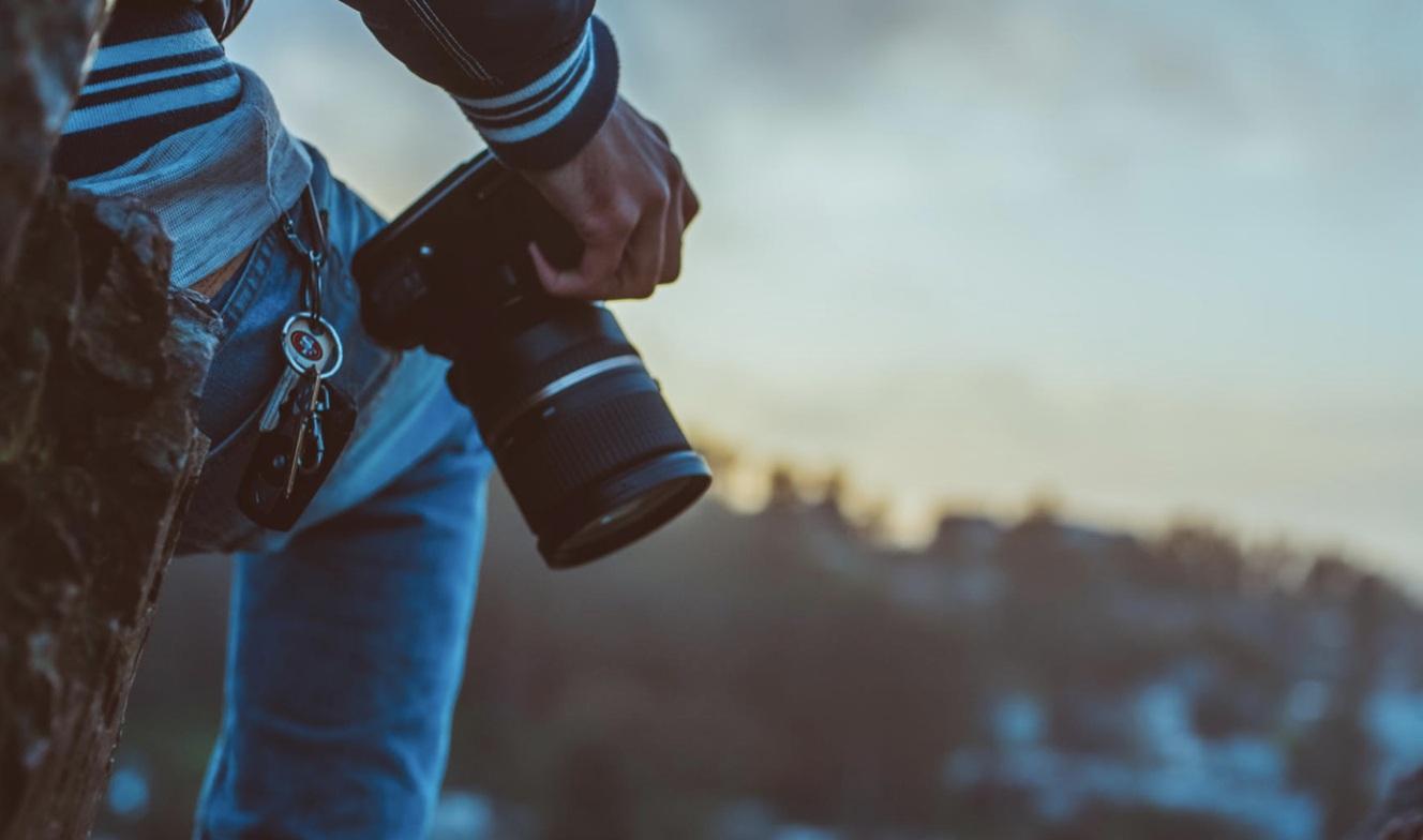 Creative desk setup with printed photos, a laptop, and camera gear arranged for visual storytelling