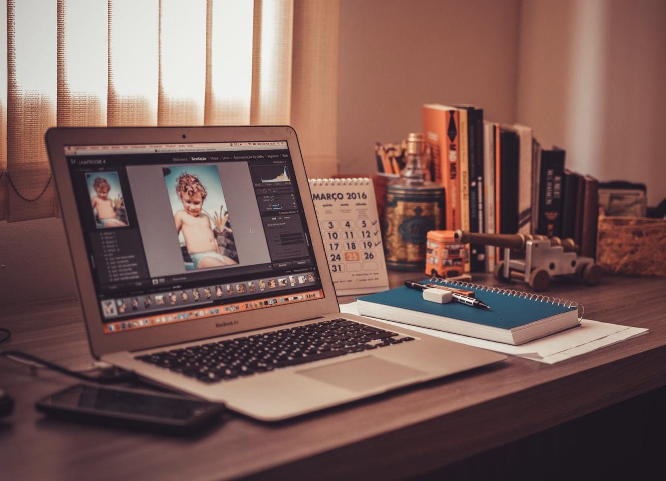Workspace with a laptop, printed photos, and camera gear arranged for visual storytelling