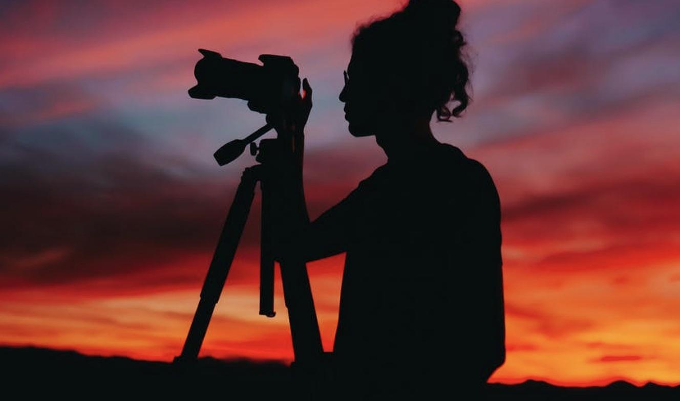 Photographer standing in a remote landscape with a camera, representing flexible plans for visual storytellers